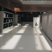 view through library with white, sun splashed floor, door open in distance with numeral 6 on it