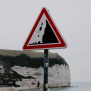 falling rocks caution sign in front of white cliffs and the sea