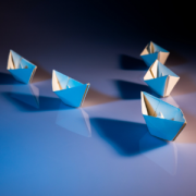 a paper boat leading two lines of paper boats