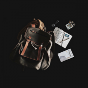 a khaki rucksack with hiking contents spread out around it, all on a black background