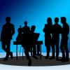 Group of business people in silhouette on blue background, most are men.